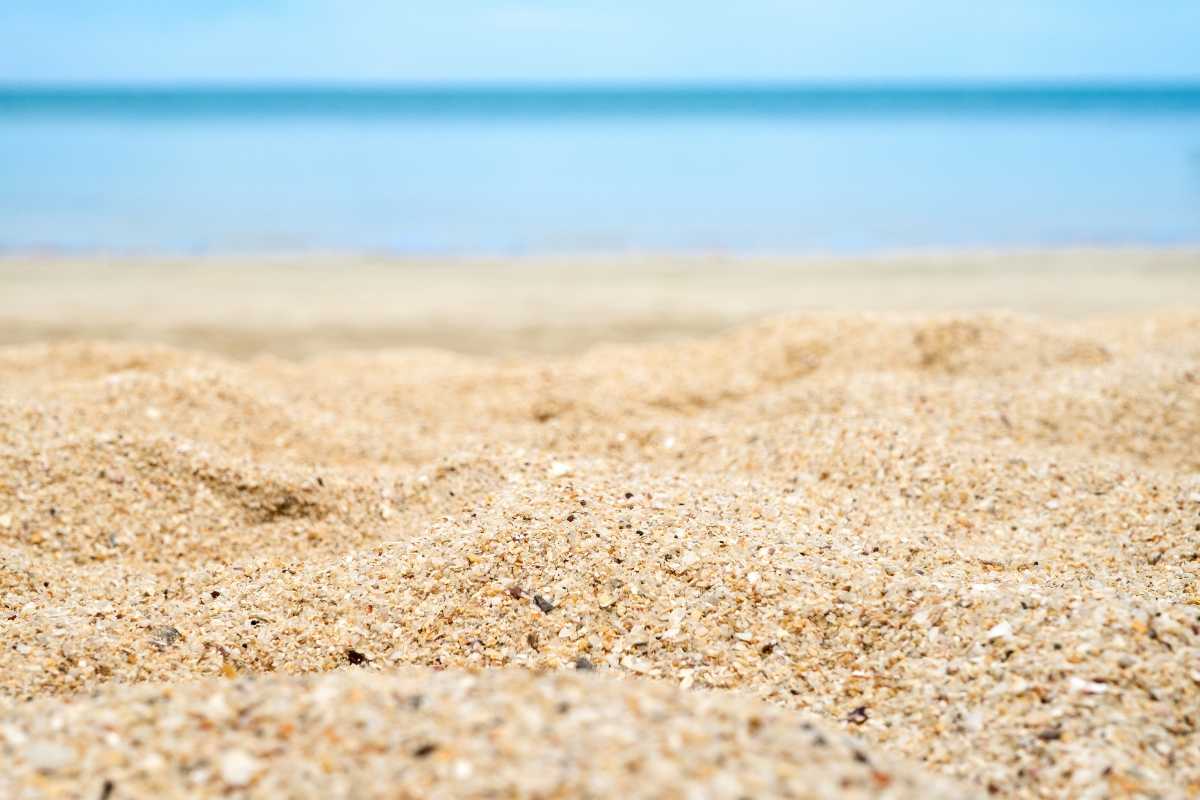 Spiaggia bianca di Porto Cesareo con bambini che giocano vicino all’acqua, ombrelloni colorati, mare cristallino sullo sfondo, atmosfera familiare
